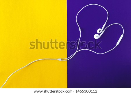 headphones in the shape of a heart on a yellow-purple background top view.