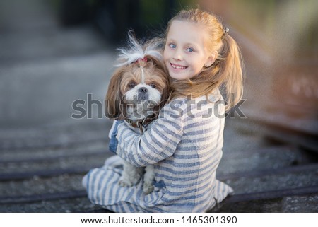 Little girl holding dog. Child with pet dog. Kid and animals friendship.