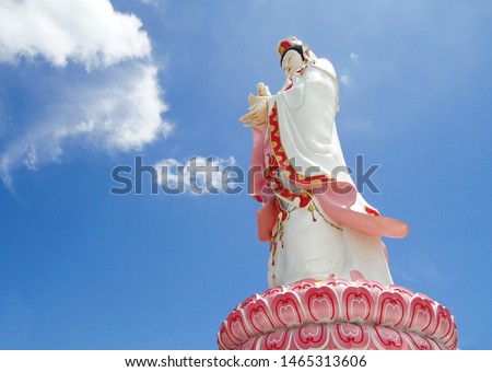 A statue of the Lady Buddha or Guan Im standing on the lotus base with sky background at noon at Wat Saman Rattanaram Temple in Chachoengsao Province. Chinese god in Thailand. Mercy and Wealthy.