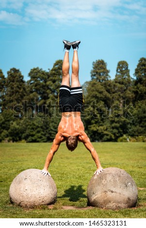 calisthenics hand stand fitness, sport, training and lifestyle concept - young man exercising on a rock outdoors in a public park