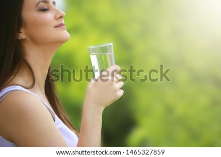 Brunette woman drinking a glass of water outside stock photo