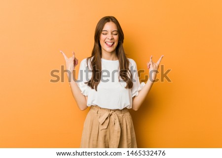 Young caucasian woman showing rock gesture with fingers