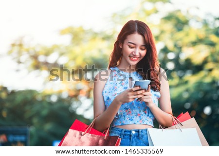 Lifestyle shopping concept, Young happy smiling asian woman with mobile phone and paper bag wearing crop top and jean in shopping street, vintage style