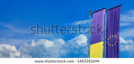 Relations between Ukraine and the European Union - two ribbons with a flag banner on flag poles against the sky with clouds and copy space for your text about political and economic cooperation.