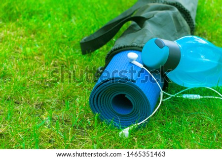 
A bottle of water on a yoga mat on fresh green grass. The concept of learning and recreation. sport and health .. Copy space.