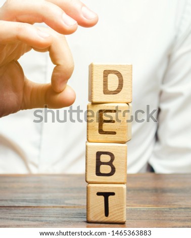 Businessman removes wooden blocks with the word Debt. Reduction or restructuring of debt. Bankruptcy announcement. Refusal to pay debts or loans and invalidate them. Debts service relief Royalty-Free Stock Photo #1465363883