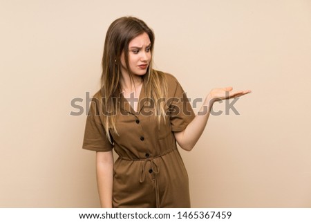 Teenager girl over isolated background holding copyspace with doubts
