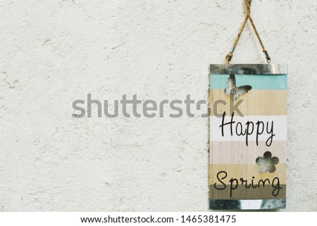 Happy spring written on an wooden board hanged on a wall. Copy space.