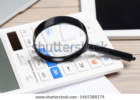 Magnifying glass and notebook on wooden table