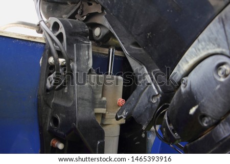 Close up lower unit of boat transom outboard motor - bracket clamp with trim and tilt cylinder and chrome rod on boat transom background Royalty-Free Stock Photo #1465393916