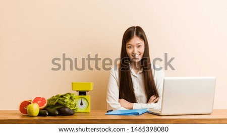 Young nutritionist chinese woman working with her laptop laughing and having fun.