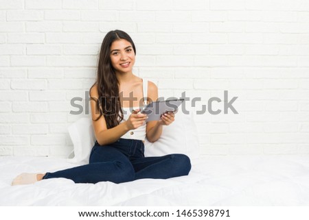 Young arab woman working with her laptop on the bed happy, smiling and cheerful.
