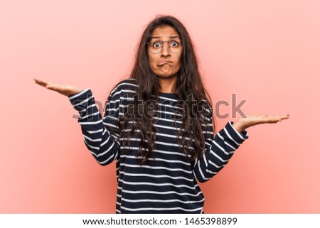 Young intellectual indian woman confused and doubtful raising him hands to hold a copy space.