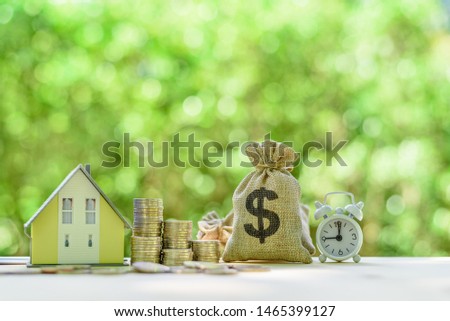 Mortgage-backed security MBS, financial concept : House model, stacks of rising coins, US dollar, money bags, a clock on a table over green background, depicts investment in home bought from the bank  Royalty-Free Stock Photo #1465399127