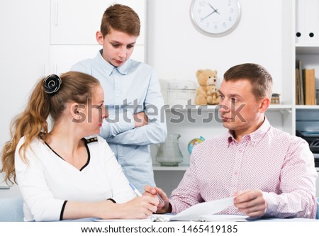 Middle-aged mother and son signing beneficial financial agreement at home