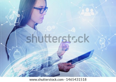 Serious young woman with tablet in blurred city with double exposure of planet hologram and business interface. Blurred toned image. Elements of this image furnished by NASA