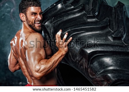 Musuclar Men Flipping Big Tire as Part of his Cross Training Royalty-Free Stock Photo #1465451582