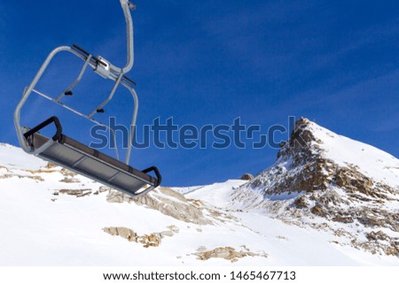 Chair lift in the foreground against the background of snow-capped mountains and blue sky.Austrian Alps in winter.