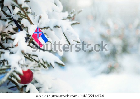 Mississippi flag. Christmas tree branch with a flag of Mississippi state. Xmas holidays greetings card. Winter landscape outdoors.