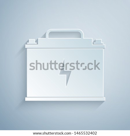 Paper cut Car battery icon isolated on grey background. Accumulator battery energy power and electricity accumulator battery. Lightning bolt. Paper art style. Vector Illustration