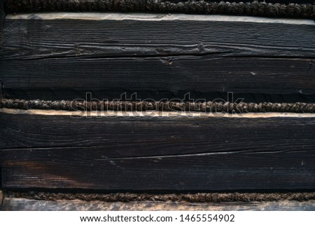 old black wooden wall of a barn - with boards and beams joined in a traditional way - wood towed