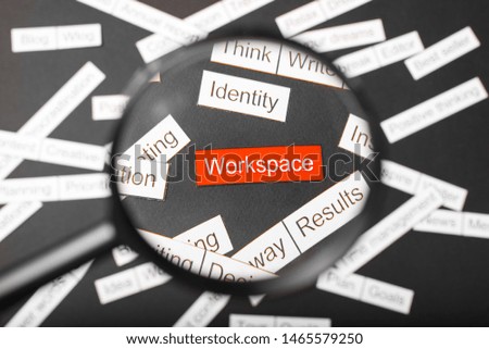 Magnifier glass over the red inscription workspace cut out of paper. Surrounded by other inscriptions on a dark background. Word cloud concept.