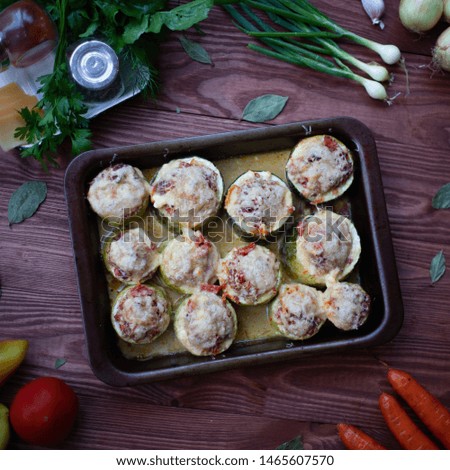 Baked vegetable marrows covered with cheese on the wooden background