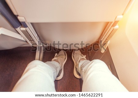 Enough legroom between the seats in the passenger plane, the view of the men's legs. Comfortable flight free space plus Royalty-Free Stock Photo #1465622291