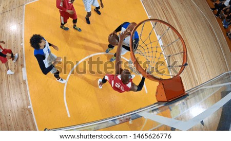 Low angle of professional basketball player in action performing slam dun in a basketball hoop on a sports arena