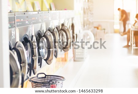 Row of industrial laundry machines in laundromat  in a public laundromat, with laundry in a basket , 
Thailand Royalty-Free Stock Photo #1465633298