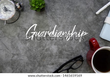 Top view of clock,plant,eyeglasses, a cup of coffee,notebook and pen on grey floor written with Guardianship. Royalty-Free Stock Photo #1465659569