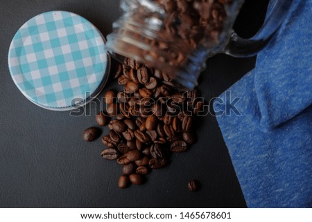 Scattered coffee beans from glass bottle isolated on black background
