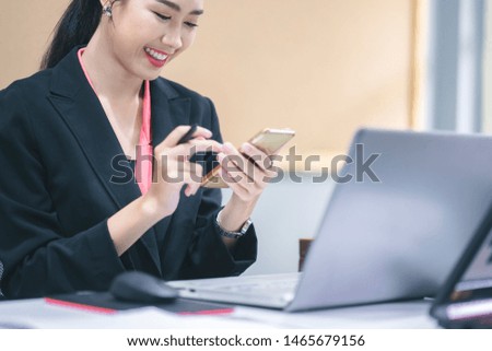 Business woman working with laptop computor and her mobile phone in the office.