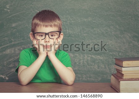 Cheerful  little boy sitting at the table. Looking at camera School concept