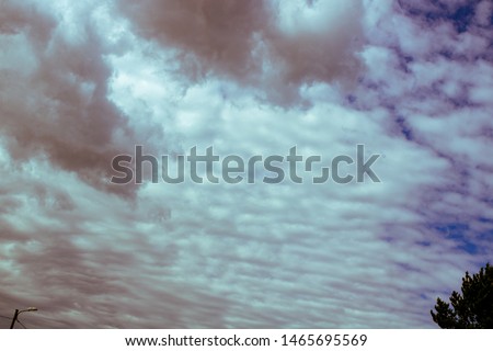 abstract background - The gathering clouds in the blue sky which are painted in a reddish shade