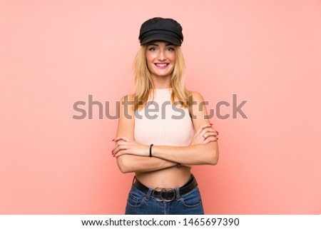 Young blonde woman with hat keeping the arms crossed in frontal position