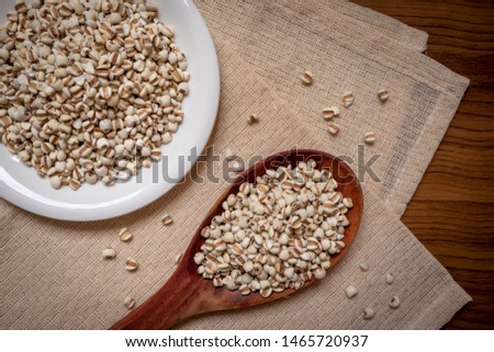 Picture of millet in a wooden spoon that is cereal and food on a brown tablecloth, wood grain, suitable for food advertising,top viwe