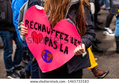 Ecological activist holds sign at rally. A closeup view of a sign written in French saying warm the hearts, not the planet. Ecological activists march on an urban street.