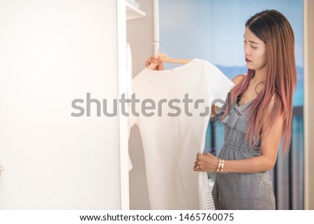 Unhappy asian woman try dress in fashion shop with serious and stress face,cost of living and social problem concept.