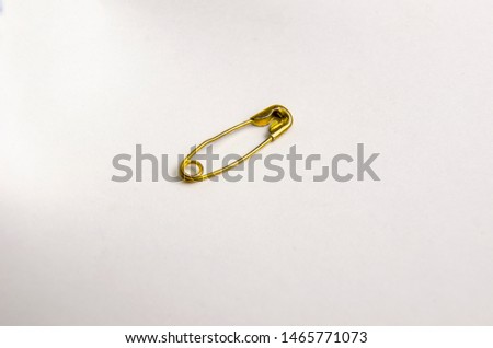 gold safety pin on white background