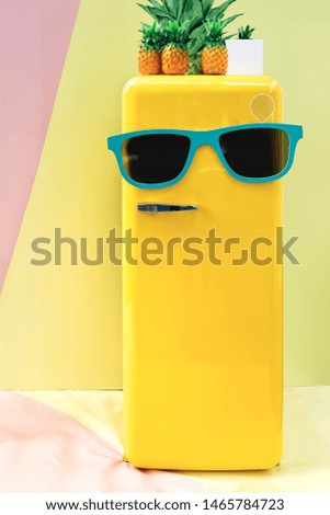 The refrigerator is painted in bright yellow and decorated with large sunglasses. Close up