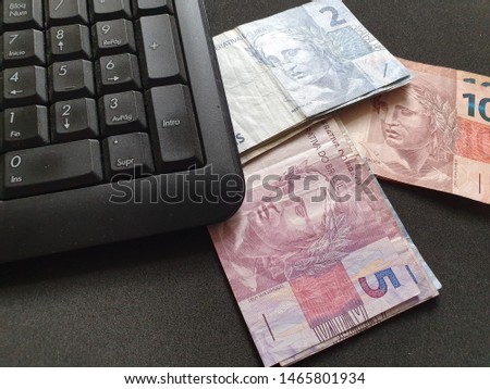 computer numeric keypad and Brazilian banknotes on black background