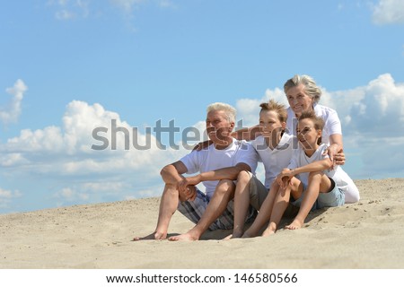cheerful boys with their grandparents walking on the sand in the summer