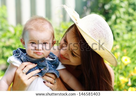 Mother with baby at outdoors in green park in a warm sunny day
