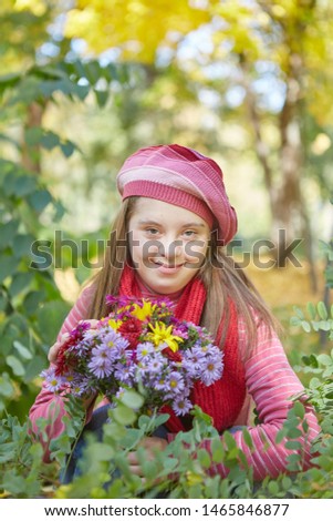 Girl with Down syndrome in autumn park. Happy and cheerful.