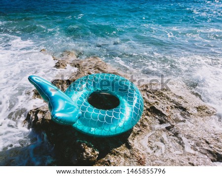 Inflated pool ring mermaid tail on a beach top view turquoise water. Summer vacation concept