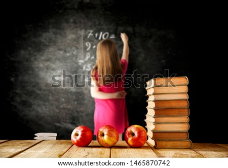 wooden top od school desk. Free space for your product. Small girl in red dress with black background wall. 