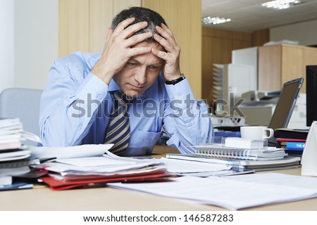 Frustrated middle aged businessman sitting at office desk Royalty-Free Stock Photo #146587283