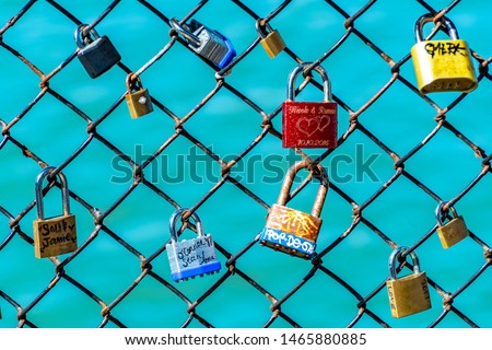 Colorful labeled padlocks/ locks locked on fence. Romantic relationship couples with names & special dates in writing. Love celebration and symbol of agreement, security, cherished moments and people.