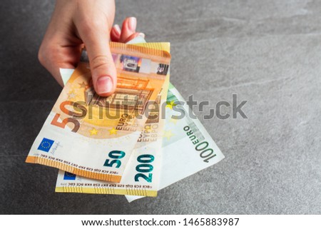 Girl giving euros, selective focus. Detail of woman hands with euro money, Euro currency offering , euro bills. charity. gray background. photo of money. payment. horizontal photo.